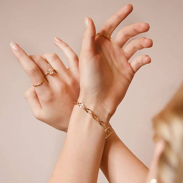 hands lifted wearing gold permanent jewelry bracelet