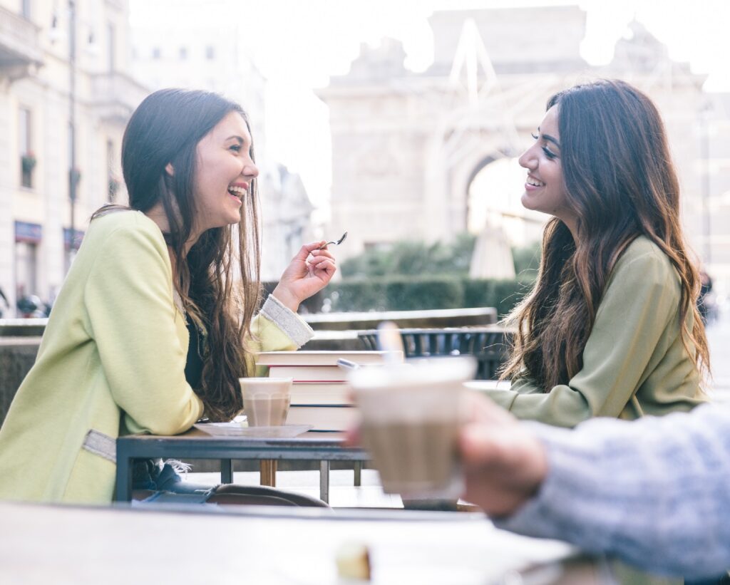 two women talking and laughing sitting at a coffee date