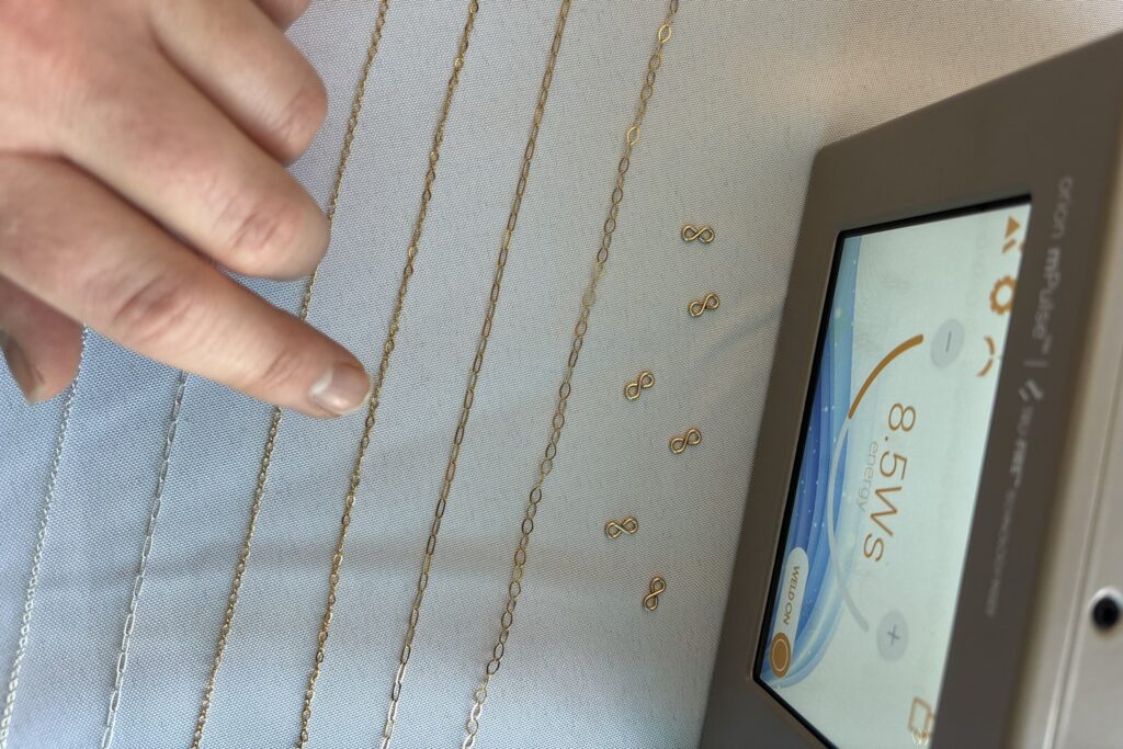 handing pointing to permanent jewelry chain and connector options