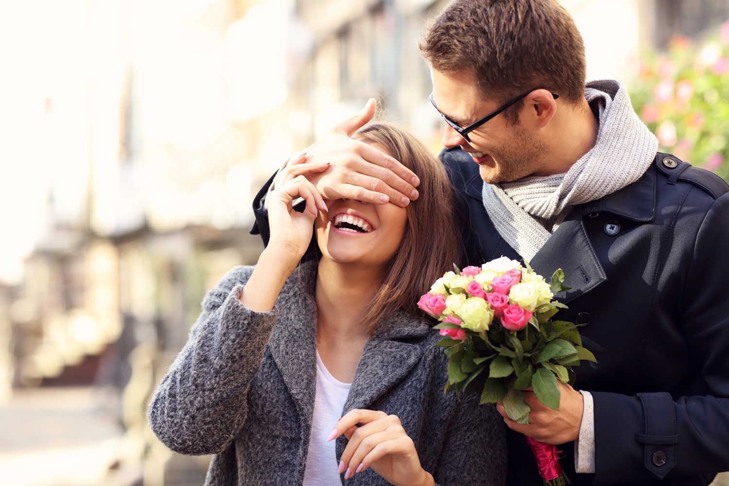 man covering woman's eyes outside of permanent jewelry boutique