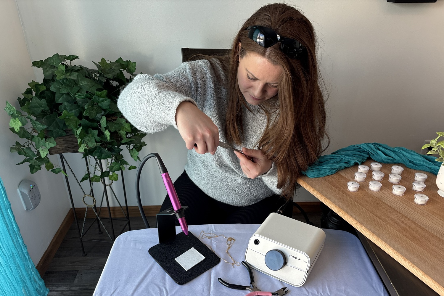 Trinity looking down working on opening a jump ring 